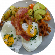 Frühstück in der Cafeteria Strana: 'SchMACofatz' - Knusprige Bratkartoffeln mit Bacon, Grillwürstchen und 2 Spiegeleiern (1,2,3,15,51) dazu ein Heißgetränek 0,2l